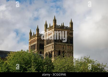 Les anciennes tours du front ouest de la cathédrale de Durham s'élèvent éclairées par le soleil du matin au-dessus d'une canopée d'arbres, ville de Durham, Angleterre. Banque D'Images