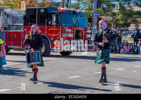 Johnson City, Tennessee, États-Unis - 7 décembre 2024 : un homme jouant des bagpips et une fille jouant de la batterie marchent dans la Parade de Noël de jour dans le centre-ville de dis Banque D'Images