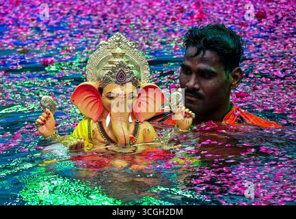Un volontaire porte une idole de la divinité hindoue Ganesha pour une immersion dans un étang artificiel pendant le festival 'Ganesh Chaturthi' à Mumbai. Banque D'Images