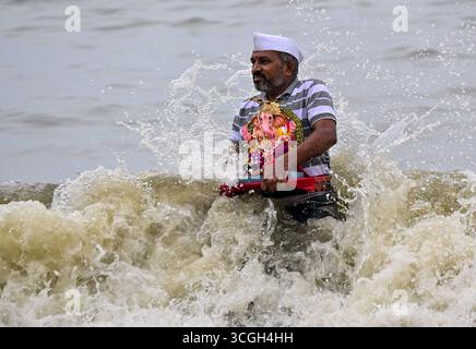 Un dévot porte une idole de la divinité hindoue Ganesha pour l'immersion dans la mer d'Arabie lors du festival 'Ganesh Chaturthi' en Mumbai.in Inde. Banque D'Images