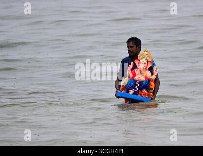 Un dévot porte une idole de la divinité hindoue Ganesha pour l'immersion dans la mer d'Arabie lors du festival 'Ganesh Chaturthi' en Mumbai.in Inde. Banque D'Images