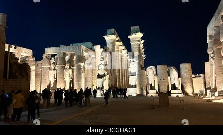Louxor, Égypte - 9 février 2025 : vue nocturne du temple de Louxor avec statues illuminées et colonnes de hall hypostyle imposantes, avec des visiteurs marchant à travers le Banque D'Images