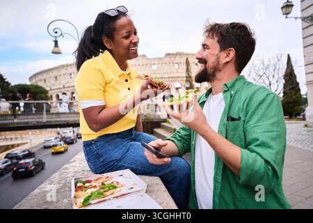 Touristes mangeant des pizzas devant le colisée à rome, italie Banque D'Images