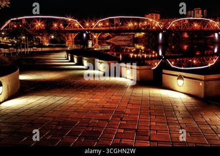 Le pont de la circulation s'est illuminé à la tombée de la nuit, projetant des reflets sur la rivière Saskatchewan Sud au centre-ville de Saskatoon. Banque D'Images