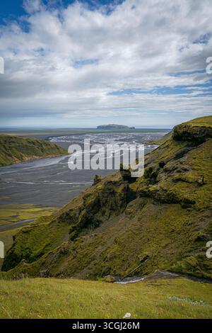 Vue surélevée sur les falaises couvertes de mousse surplombant les canaux fluviaux tressés qui coulent à travers une plaine de sable noir en Islande Banque D'Images
