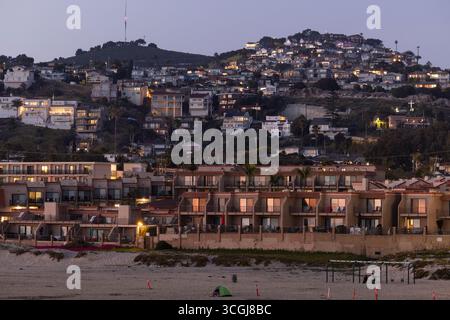 Pismo Beach, Californie, États-Unis - 20 avril 2025 : les gens apprécient la plage au coucher du soleil devant les hôtels et les maisons. Banque D'Images