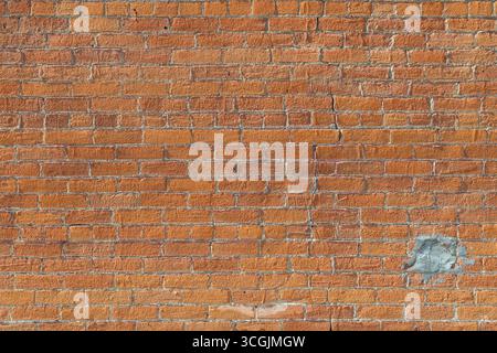 Fond de texture abstrait d'une surface murale de briques de couleur orange vintage extérieure altérée, avec une fondation en calcaire beige au fond Banque D'Images