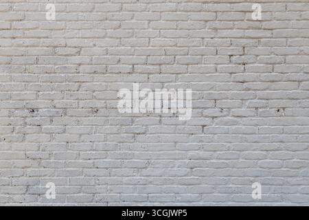 Fond de texture abstraite plein cadre d'un mur de briques antiques peint blanc grungy qui montre une certaine peinture de vieillissement et de pelage Banque D'Images