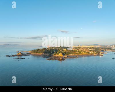 Vue panoramique sur la ville côtière de Xiamen, en Chine, mettant en valeur une île avec des bâtiments et des eaux bleues calmes sous un ciel clair. Banque D'Images