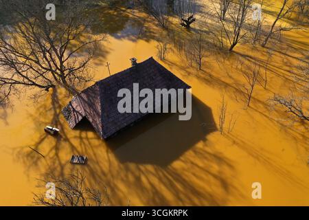 Vue aérienne de la maison de village en train de couler au milieu de l'étang de décantation de drainage de mine acide toxique. Geamana, Rosia Montana, Roumanie Banque D'Images