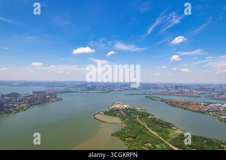 Jiangxia District présente un vaste paysage urbain et un lac serein d'une perspective aérienne à Wuhan, en Chine, sous un ciel dégagé. Banque D'Images