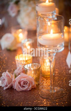 Roses roses et bougies flottantes sur la table de mariage étincelante Banque D'Images