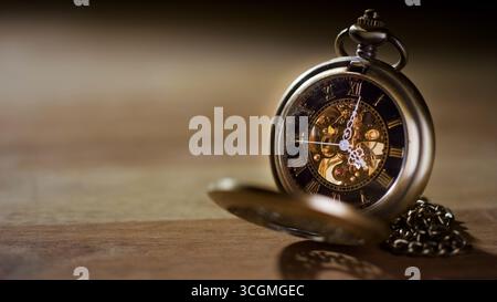 Une montre de poche antique complexe repose sur une surface en bois, mettant en valeur ses mécanismes détaillés et son charme vintage. Banque D'Images