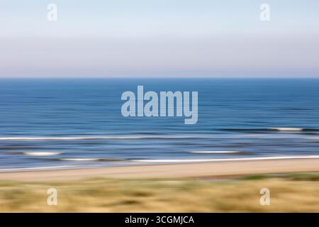 Les couleurs pastel douces se fondent parfaitement dans une scène océanique floue, créant des lignes horizontales abstraites tandis que les vagues roulent doucement vers le rivage au crépuscule Banque D'Images