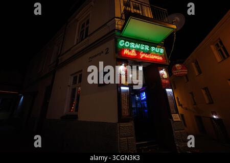 Rzeszow, Pologne - 22 août 2025 : un pub d'angle confortable illuminé avec des enseignes au néon à Rzeszow, Pologne, la nuit. Banque D'Images