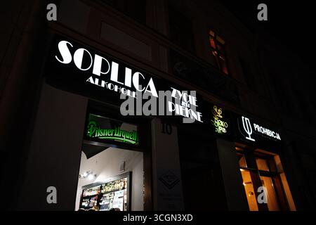 Rzeszow, Pologne - 22 août 2025 : vue sur la rue de la boutique et de la signalisation du bar allumée la nuit, représentant la vie nocturne et la culture Banque D'Images