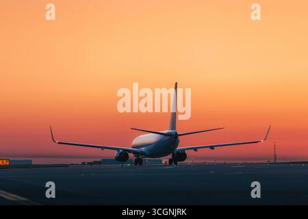 Trafic à l'aéroport au lever du soleil doré. Plan large d'un avion de passagers décollant de la piste. Banque D'Images