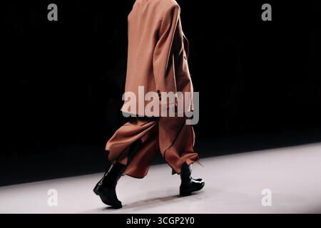 Costume classique marron, veste, jupe longue et bottes en cuir noir. Défilé de mode défilé de mode de marche de mannequin Banque D'Images