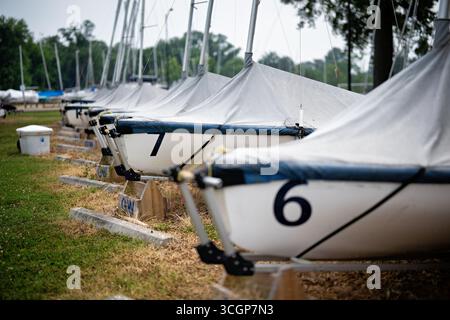 Washington Sailing Marina Potomac River rangée de voiliers couverts Arlington // WASHINGTON DC — Une rangée de voiliers couverts est entreposée sur terre à la Washington Sailing Marina, une installation populaire sur le fleuve Potomac. Ces petits navires, dont certains sont marqués par des chiffres comme '6' et '7', sont utilisés pour la navigation de plaisance et les programmes d'instruction. Les marquages « GW » sur les stands de bateaux suggèrent une affiliation avec le George Washington University Sailing Club, qui est basé à la marina. La marina de voile de Washington offre des cales de bateau, des entrepôts secs et des leçons de voile pour le public. Bien qu'officiellement localisé Banque D'Images