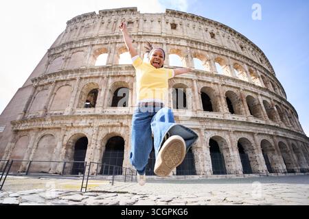 Femme heureuse sautant devant le Colisée de Rome Banque D'Images