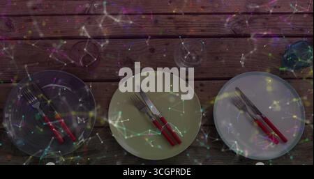 Montrant trois assiettes rondes avec des couverts à poignée rouge et des verres sur une table en bois, superposition de réseau Banque D'Images