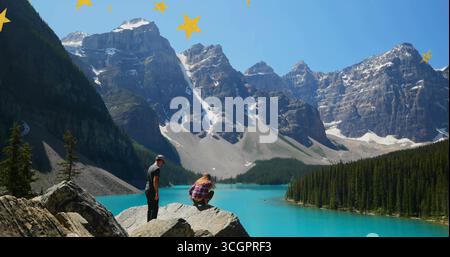 Observez un couple sur un rocher surplombant un lac turquoise, des sommets enneigés, des superpositions d'étoiles, un espace de copie Banque D'Images