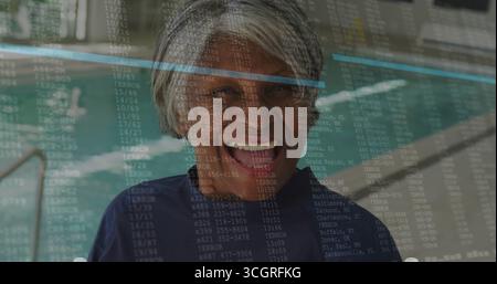 Femme senior debout portant chemise de bain marine sur la terrasse de la piscine par échelle en acier, superposition de code numérique Banque D'Images