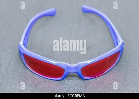 Lunettes de soleil sport tendance avec monture bleue et verres rouges gros plan Banque D'Images