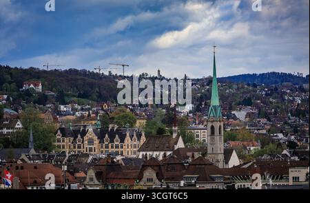 Une vue aérienne de la ville avec ses bâtiments historiques, ses flèches d'église proéminentes et ses collines boisées sous un ciel nuageux à Zurich, en Suisse Banque D'Images