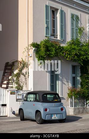 Une petite voiture Citroen ami tout électrique garée devant une maison traditionnelle Banque D'Images
