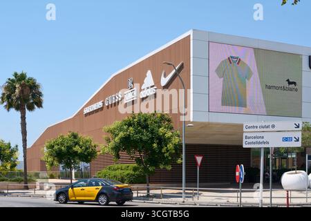 Viladecans. Barcelone - 29 août 2025 : les logos de Nike, Adidas, Guess et Skechers se distinguent sur la façade en bois des Viladecans The style Outlets Banque D'Images