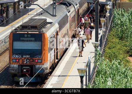 Viladecans. Barcelone - 29 août 2025 : voyageurs embarquant et descendant d'un train Rodalies arrêté sur le quai animé de la gare de Viladecans. Banque D'Images