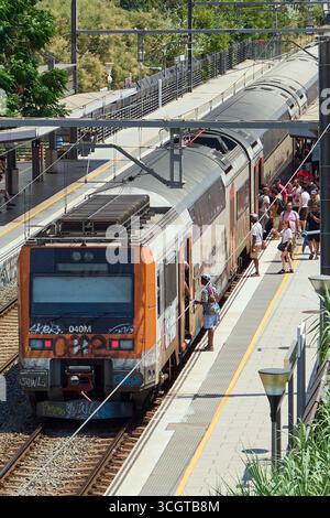 Viladecans. Barcelone - 29 août 2025 : un train de banlieue Rodalies s'arrête dans la gare alors que les passagers attendent sur le quai pour monter à bord. Banque D'Images