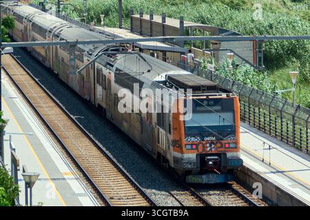 Viladecans. Barcelone - 29 août 2025 : un train Rodalies, avec des graffitis sur son front, se déplace le long des voies de la gare de Viladecans vu d'un ov Banque D'Images