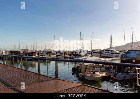 une marina sereine mettant en vedette plusieurs bateaux et yachts amarrés à l'embarcadère sous un ciel dégagé Banque D'Images