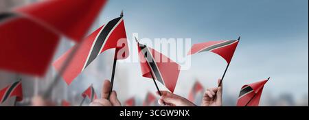 Drapeaux de Trinité-et-Tobago dans leurs mains sur un fond urbain flou Banque D'Images