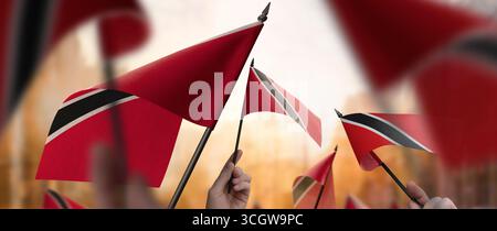Drapeaux de Trinité-et-Tobago dans leurs mains sur un fond urbain flou Banque D'Images
