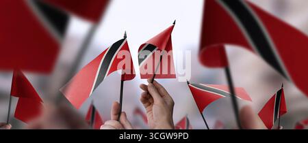 Drapeaux de Trinité-et-Tobago dans leurs mains sur un fond urbain flou Banque D'Images