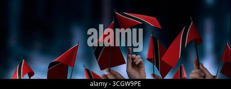 Drapeaux de Trinité-et-Tobago dans leurs mains sur un fond urbain flou Banque D'Images