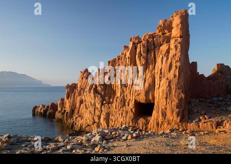 Arbatax, Tortolì, Ogliastra, Sardaigne, Italie. Falaises de porphyre rouge surplombant le rivage rocheux de la Baia delle Rocce Rosse, coucher de soleil. Banque D'Images