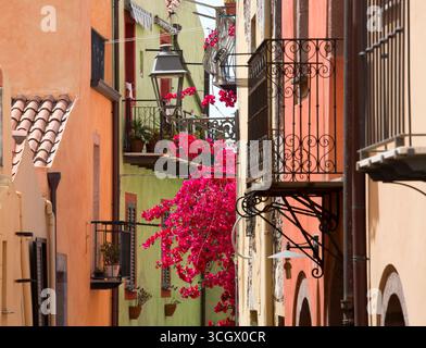 Bosa, Oristano, Sardaigne, Italie. Façades pastel et balcons en fer forgé dans le quartier historique de sa Costa, bougainvilliers roses bien en vue. Banque D'Images