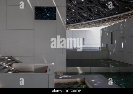 Eau - Abu Dhabi - Louvre bassins tranquilles - canaux d'eau calmes et marches ombragées sous le toit à motifs Banque D'Images
