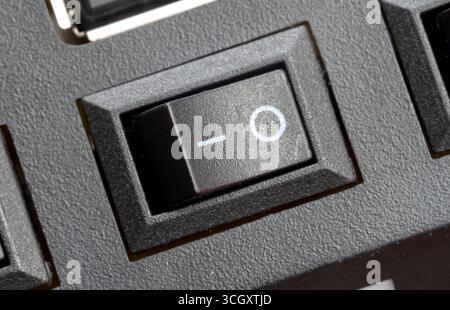 Macro gros plan d'un interrupteur d'alimentation à bascule noir en position OFF sur un cercle générique d'appareil électronique et symboles de ligne sur plastique texturé deux Banque D'Images