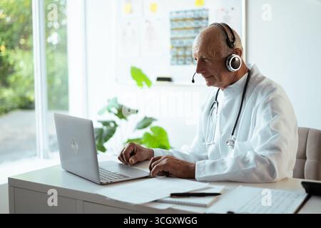 Vieil homme médecin travaillant en ligne consultant patient en concept de télémédecine Banque D'Images