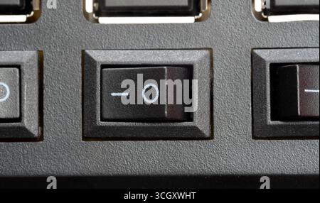 Macro vue de dessus d'un interrupteur d'alimentation à bascule en position on, bouton en plastique noir sur un panneau d'appareil électronique générique, gros plan d'un contrôle matériel Banque D'Images