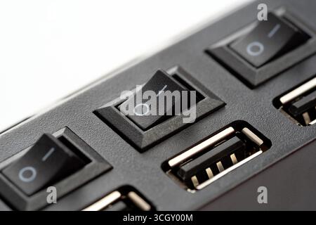 Macro gros plan d'un concentrateur USB avec plusieurs ports et interrupteurs d'alimentation en position OFF, détail du boîtier en plastique noir montrant la commande manuelle pour le connecteur de l'appareil Banque D'Images