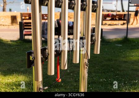Une structure musicale unique faite de tubes métalliques se dresse dans un parc au bord de l'eau, offrant une opportunité créative pour les visiteurs de jouer de l'instrument Banque D'Images