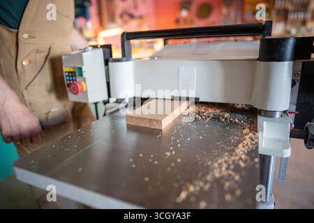 Artisan qualifié travaillant avec du bois sur raboteuse à jointure épaisse, préparant des matériaux de meubles Banque D'Images