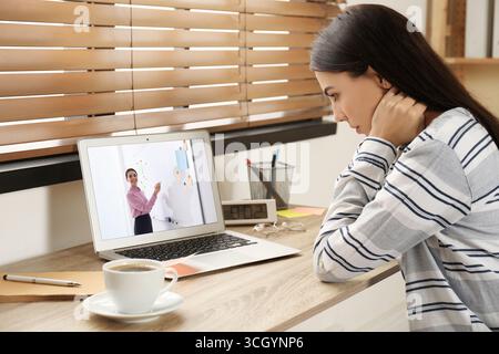 Concept d'apprentissage en ligne. Étudiant ayant un chat vidéo en ligne avec le professeur via ordinateur portable au bureau Banque D'Images