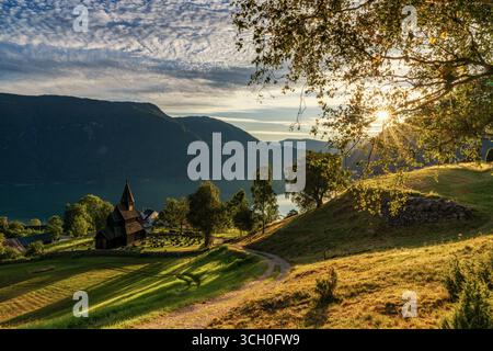 Urnes, Norvège - 24 août 2025 : village d'Ornes et l'église historique des urnes Stave sur le Lustrafjorden en Norvège au coucher du soleil Banque D'Images